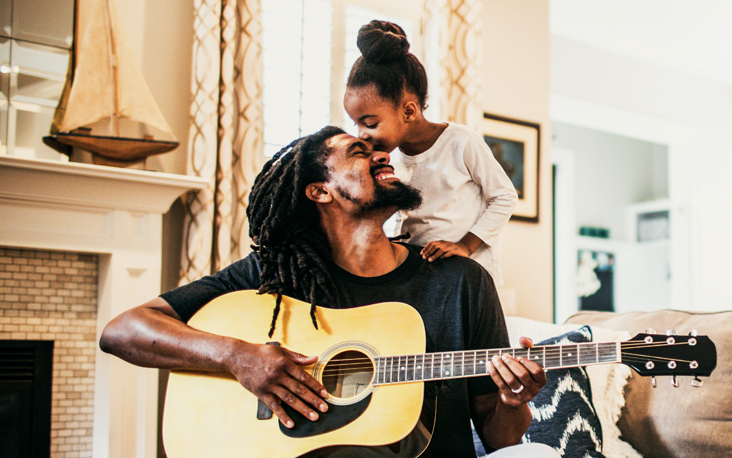 Father playing guitar to his young daughter